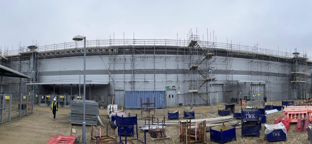 Access scaffolding and a stair tower around the curved exterior of Diamond Light Source at Harwell