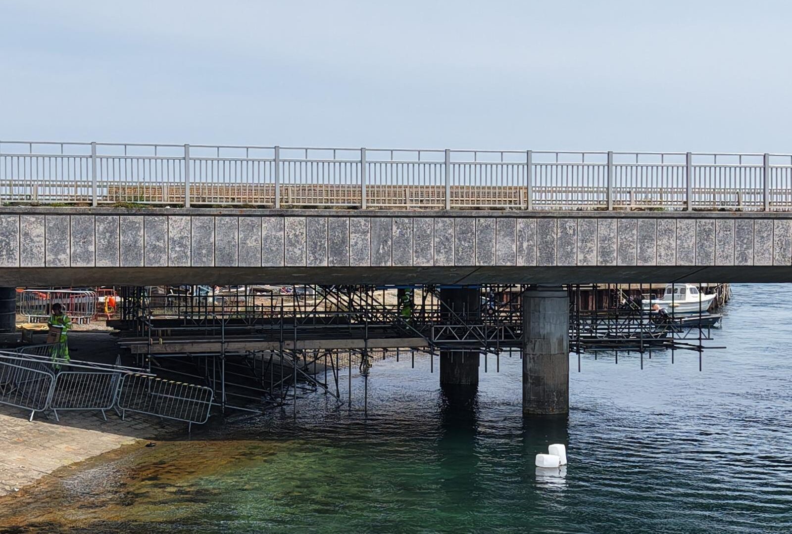 Suspended access scaffolding beneath Ferry Bridge in Weymouth, viewed from the water’s edge