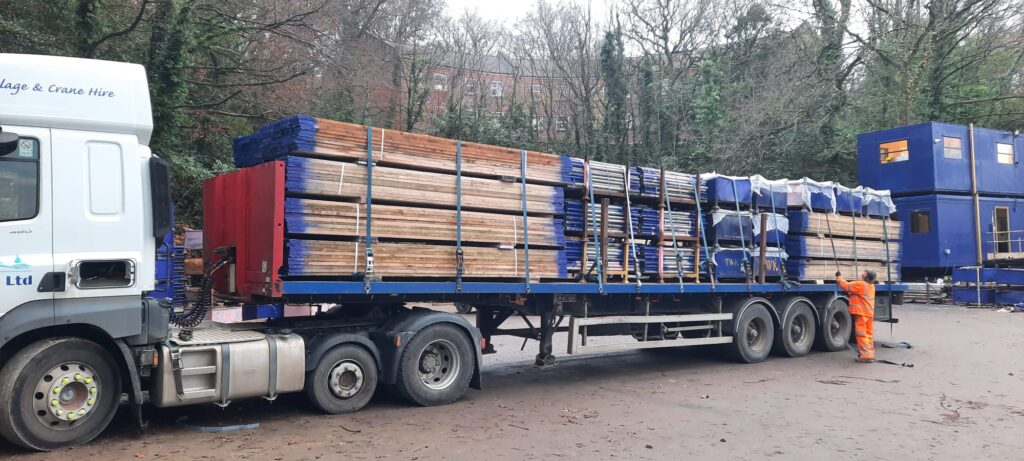 Scaffold boards, tube and TWK-branded equipment bags stacked on a flatbed trailer